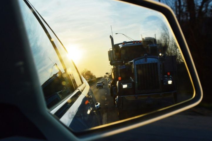 Commercial semi truck approaching a restored muscle car on the highway